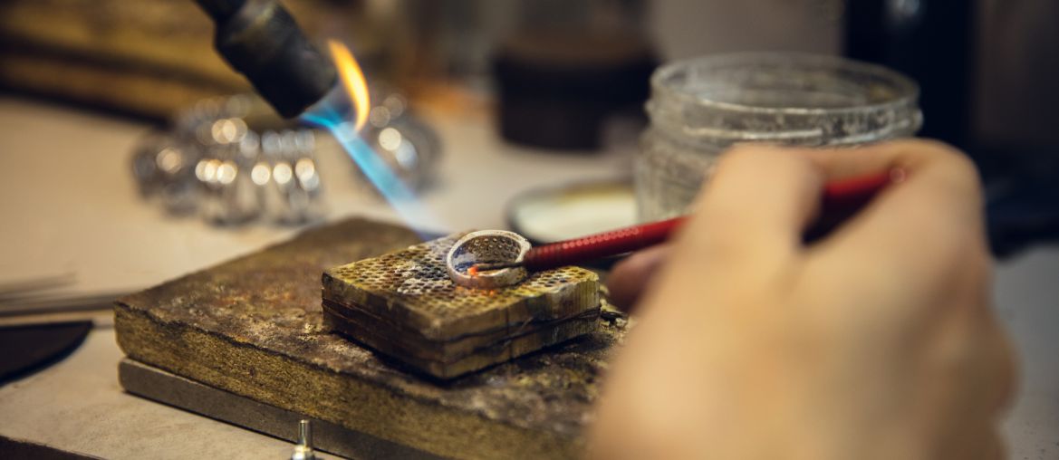 close up hands jeweller goldsmiths making golden ring with gemstone using professional tools 1 1